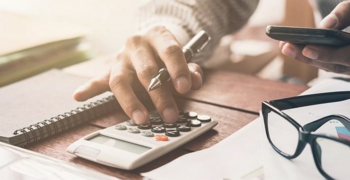 A person holding a calculator and a cell phone.