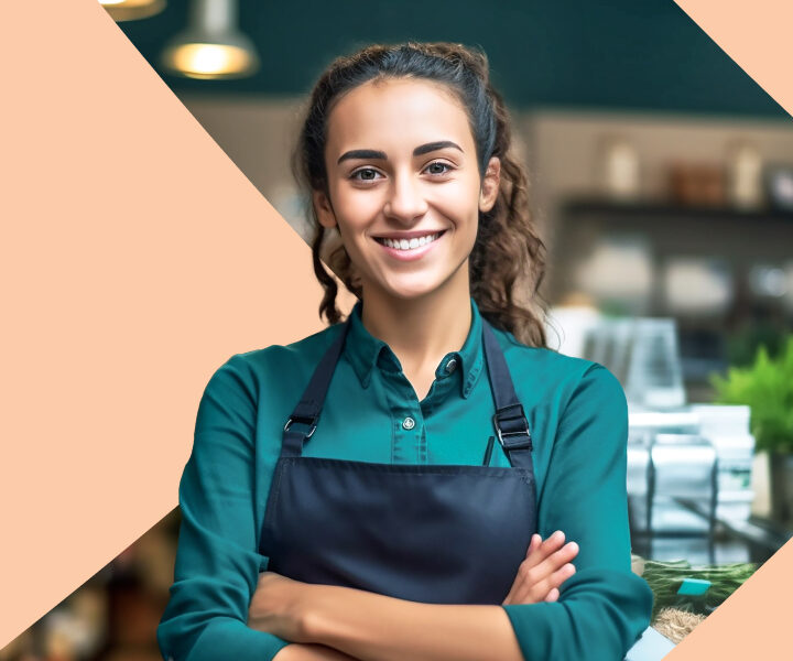 A person standing with a green shirt and a blue apron.