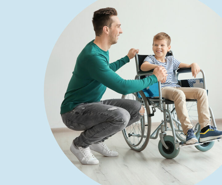 A person is talking to a child sitting in a wheelchair.