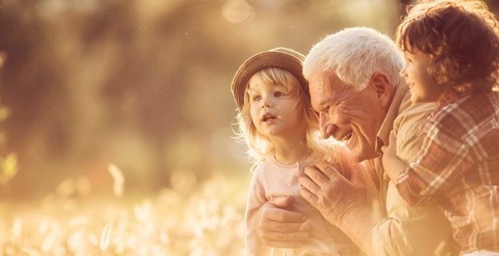 An older person holding a child in his arms.