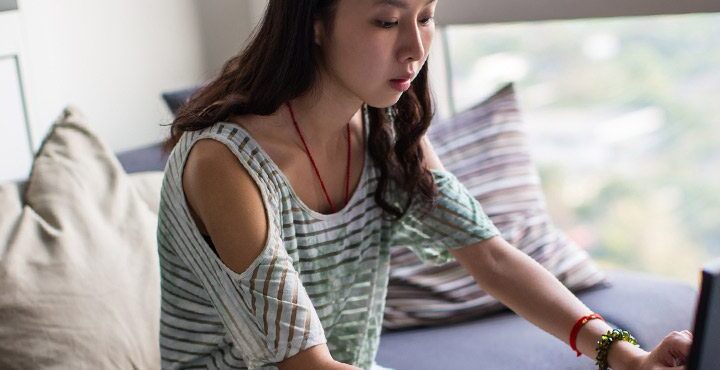 A person sitting on a bed with a laptop.