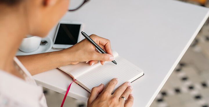 A person holding a pen and a notebook.