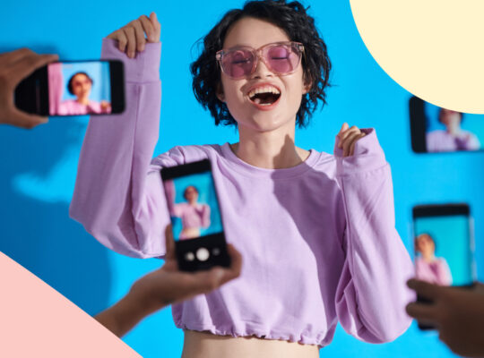 A person poses in front of a blue wall.