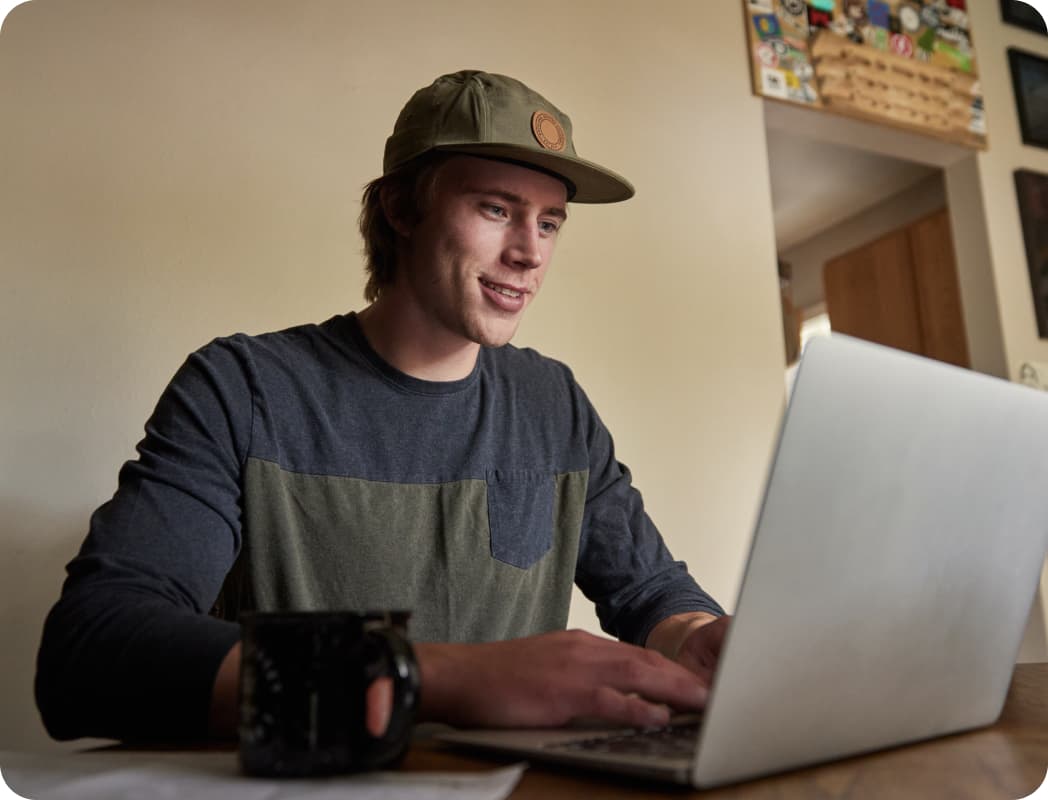 TurboTax customer Drew smiles as he looks down at his laptop.