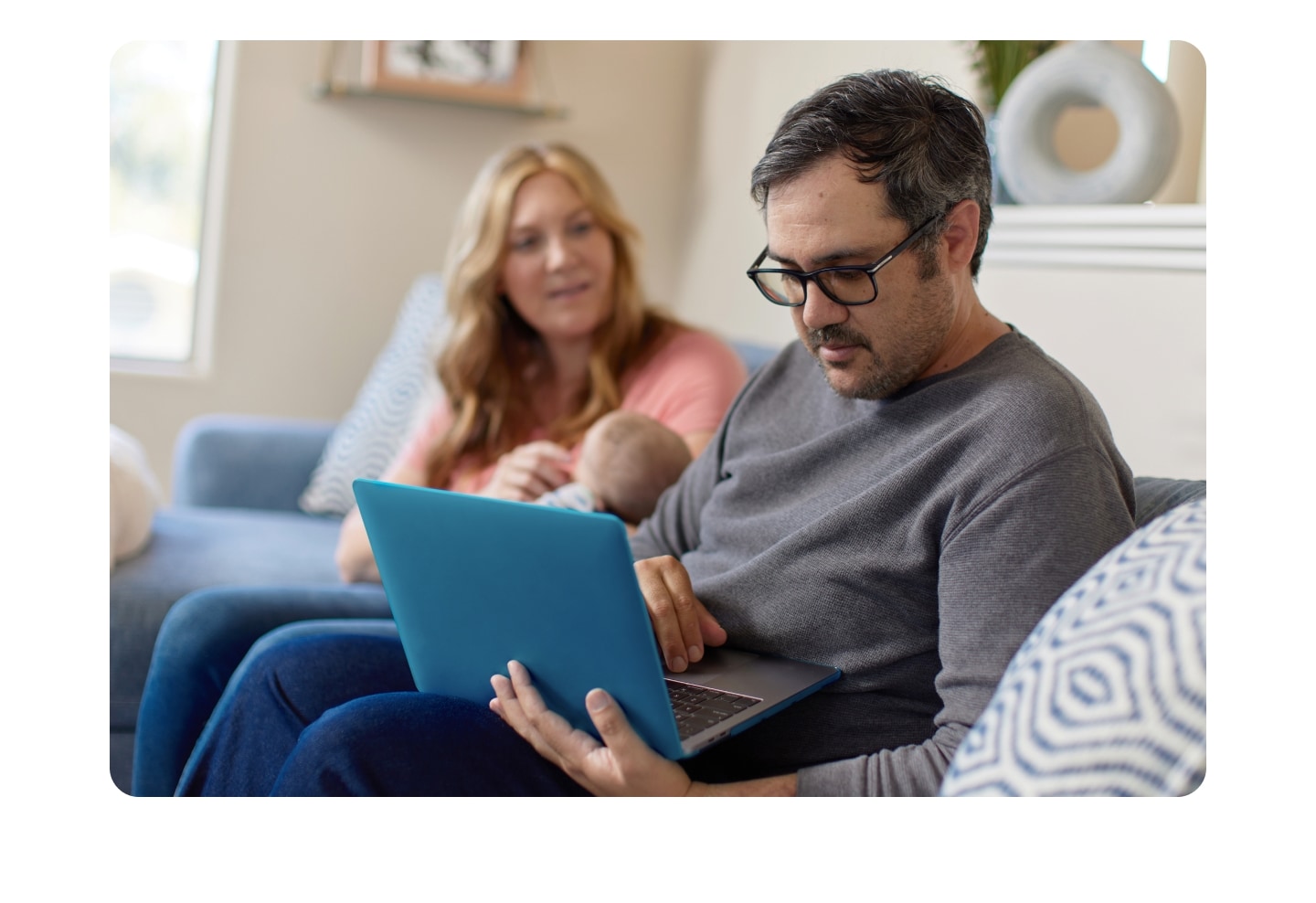 A person and a person sitting on a couch with a baby.