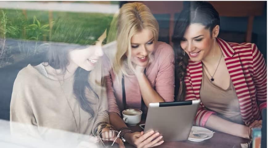 Three people sitting on a couch looking at a laptop.