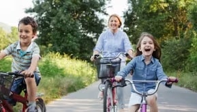 A person and a young person riding bikes down a street.