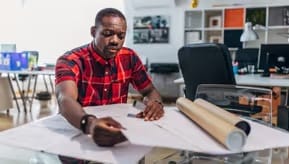 A person sitting at a desk with a laptop and a pen.