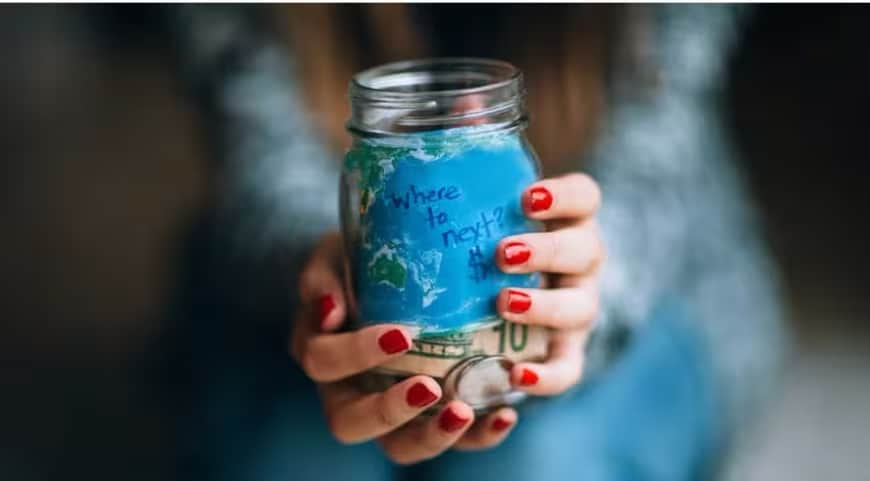 A person holding a jar filled with paint and a cell phone.