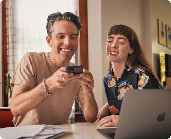 TurboTax customer Moira and her husband smile as he uses his phone to photograph and upload their tax documents.