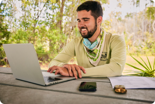  TurboTax customer Michael is seated with his laptop open, smiling. 