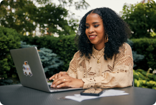 TurboTax customer Keewa is seated with her laptop open, smiling. 