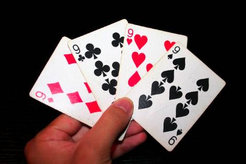 hand with 4 playing cards with the number 9