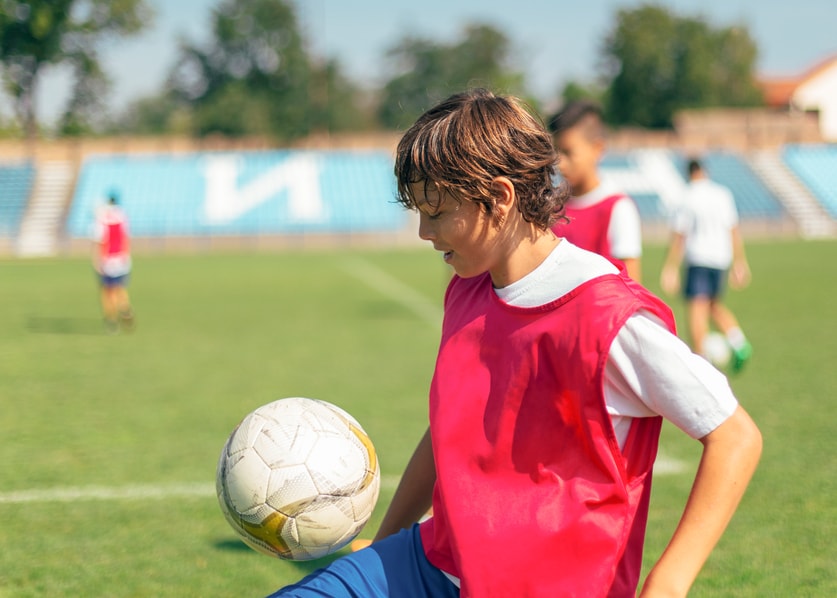 Boy kicking soccer ball with his knee