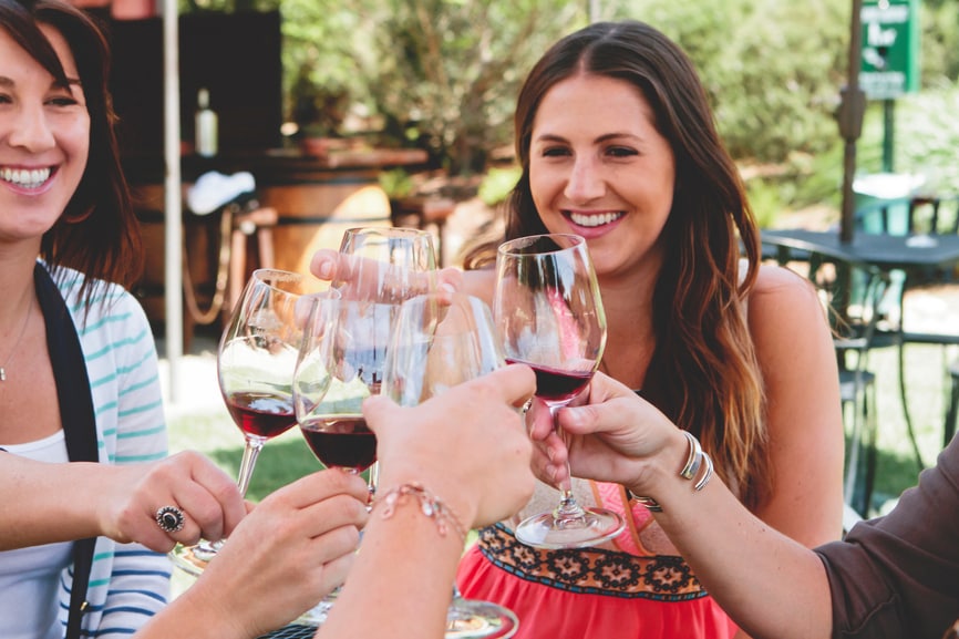 Several female friends toasting glasses of wine to their tax refund success.