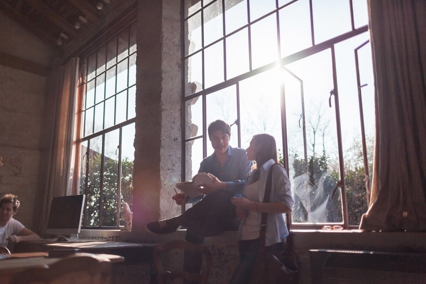 Two people sitting in a well lit window space