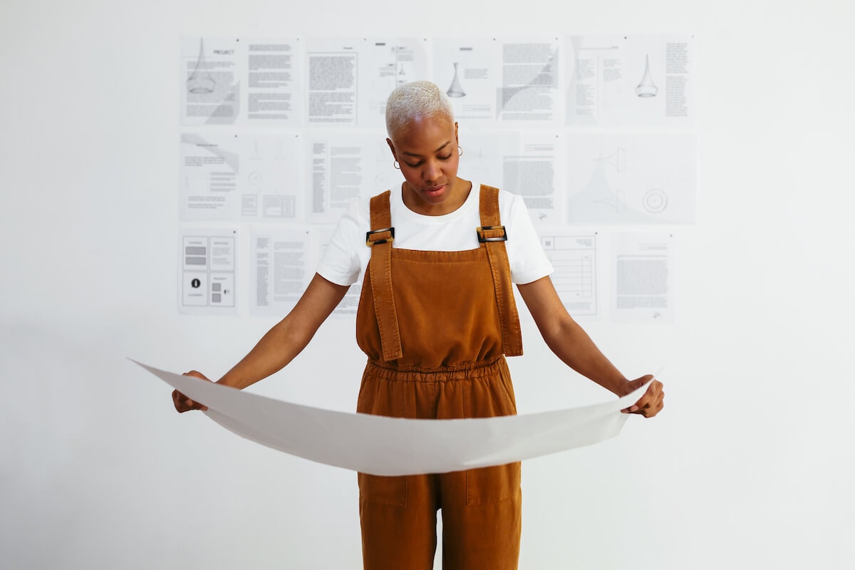 A Black woman looks over design schematics.