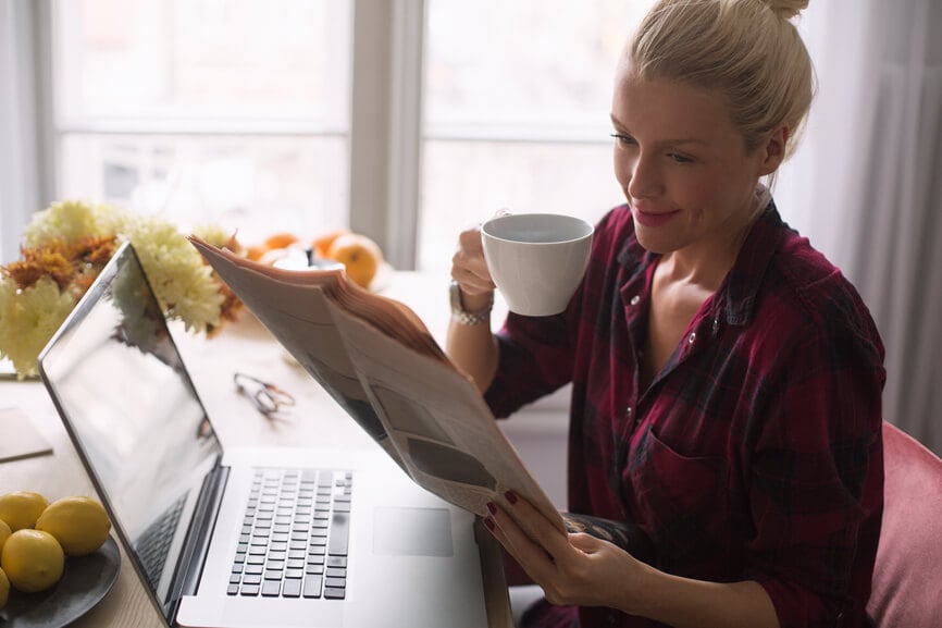 Woman drinking coffee and reading her newspaper.