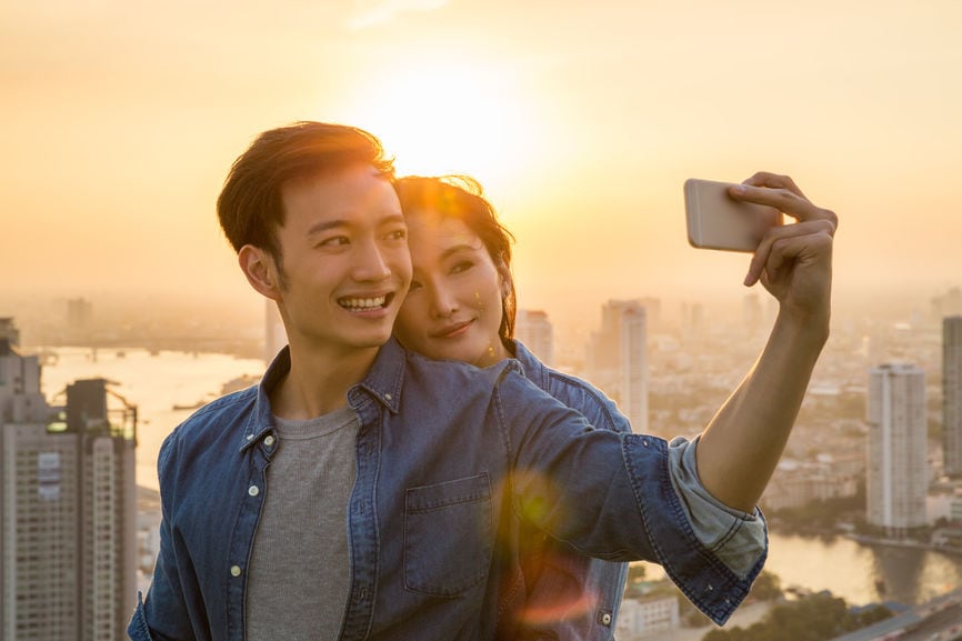 Smiling Young Couple Taking A Selfie At Sunset