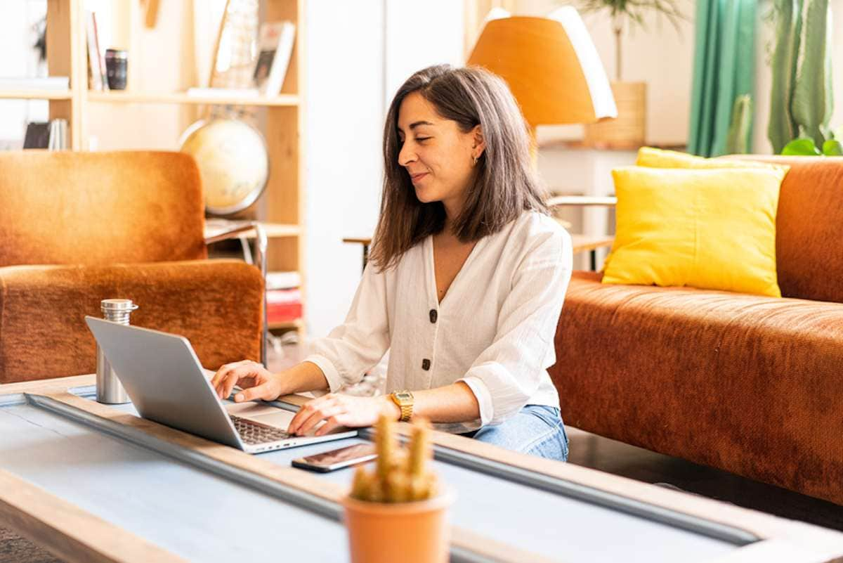 Young woman sits on the floor at a low table and works on a laptop