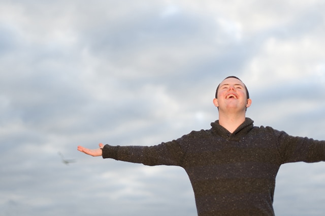 Joyful man holds arms out and looks up