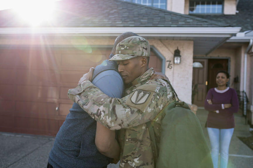 military man hugging his family