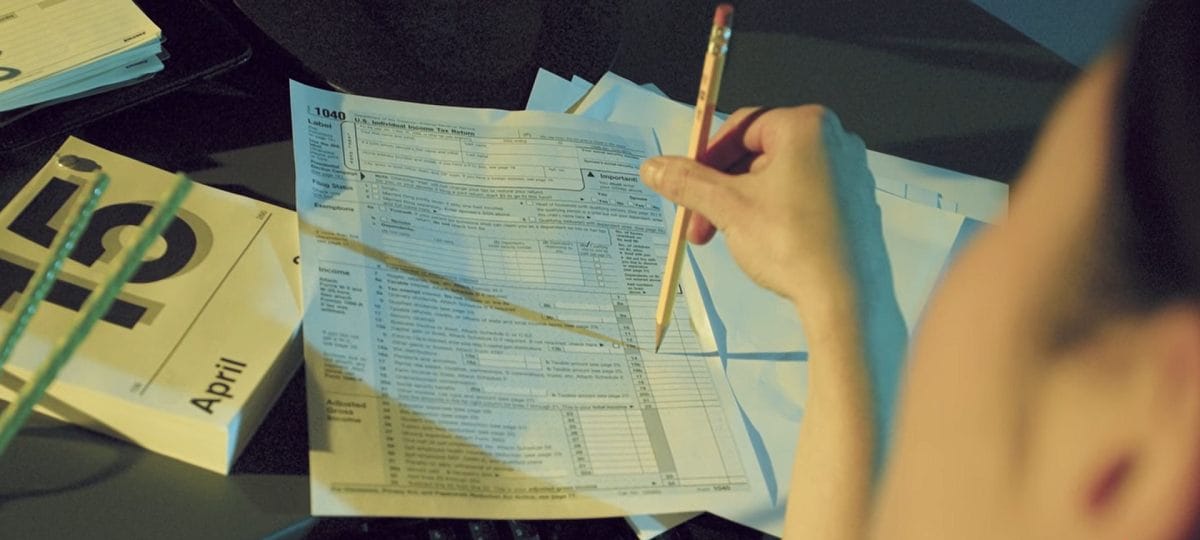close-up of a person filling in tax forms with a pencil