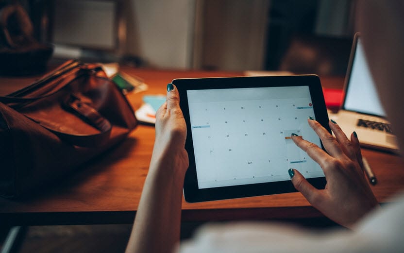 Businesswoman on tablet scheduling on her calendar