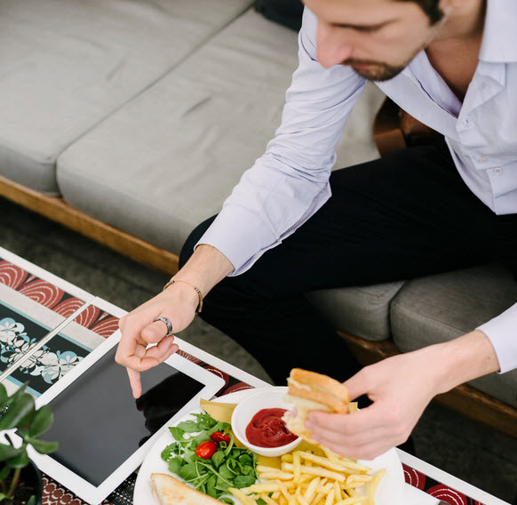 A man seated at a table in front of burgers and fries