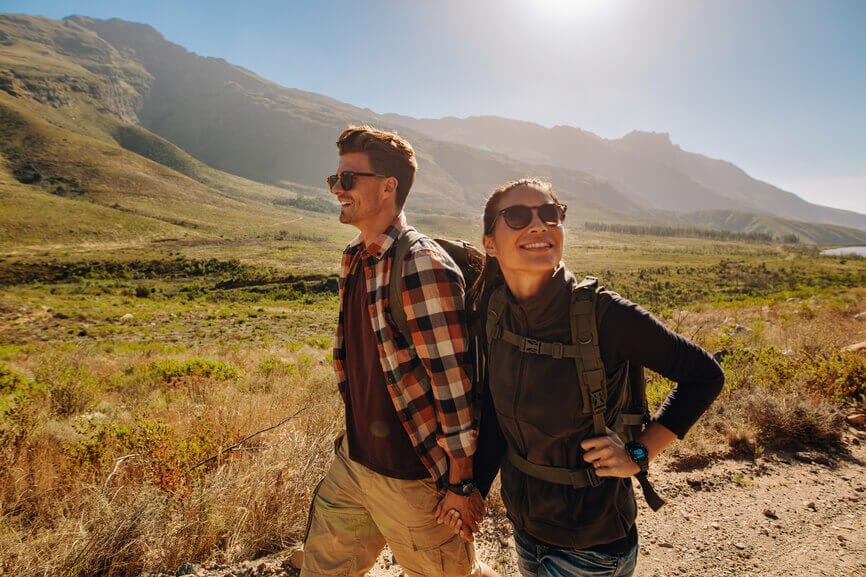A couple enjoying the sunshine and landscape on a hike.