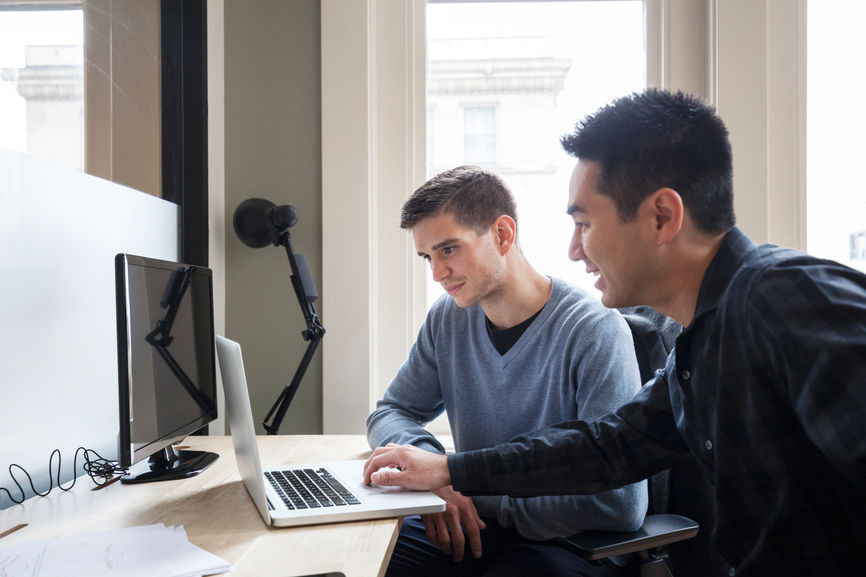 Mixed race students studying together on a laptop at a shared desk