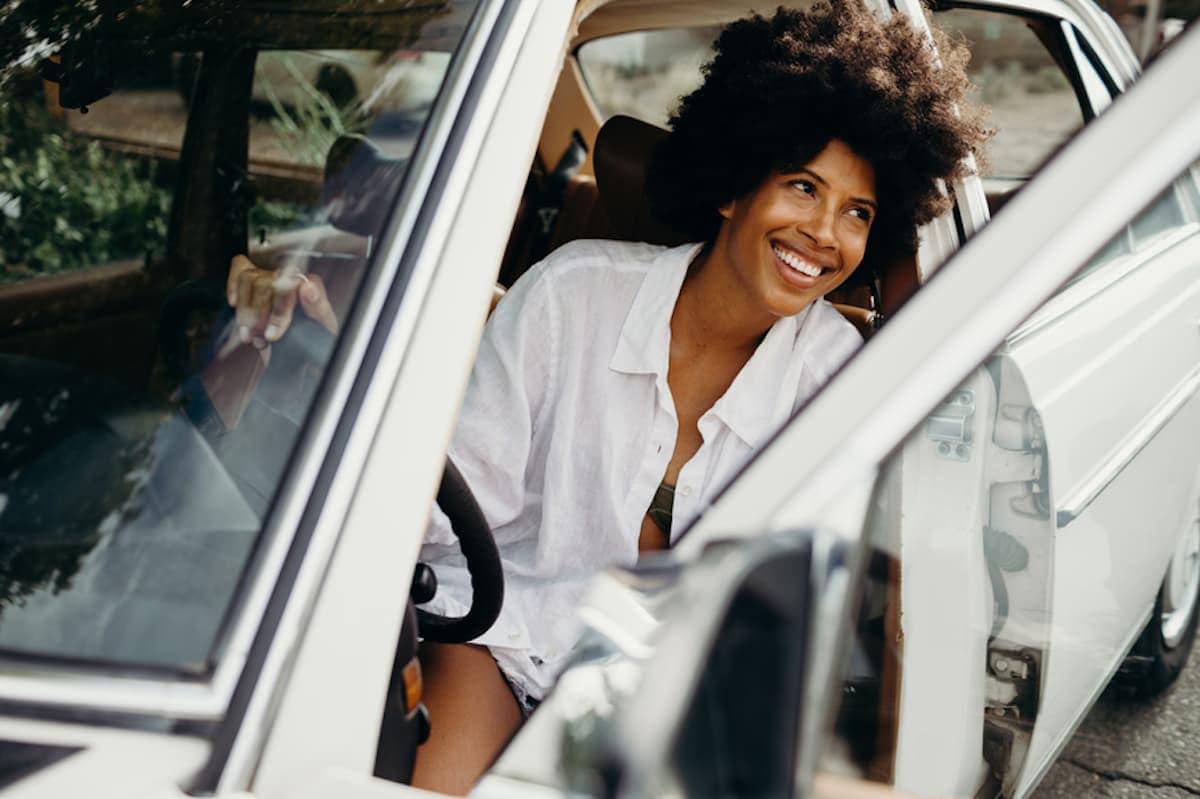 Smiling woman stepping out of her car