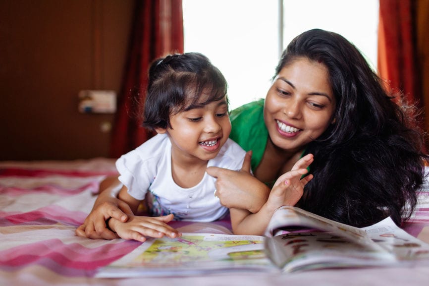 Little Girl Sharing A Cheerful Moment With Her Mother While Studying