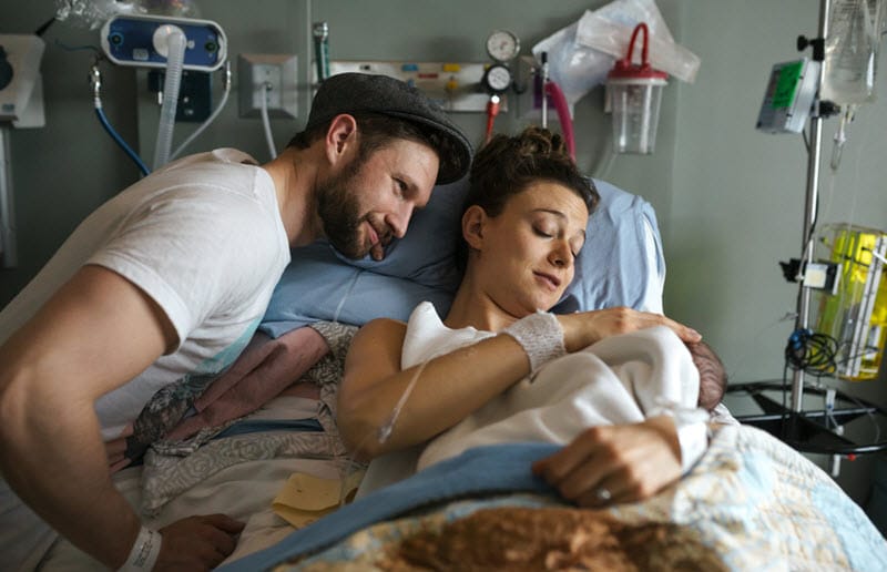 Couple holding newborn in hospital bed