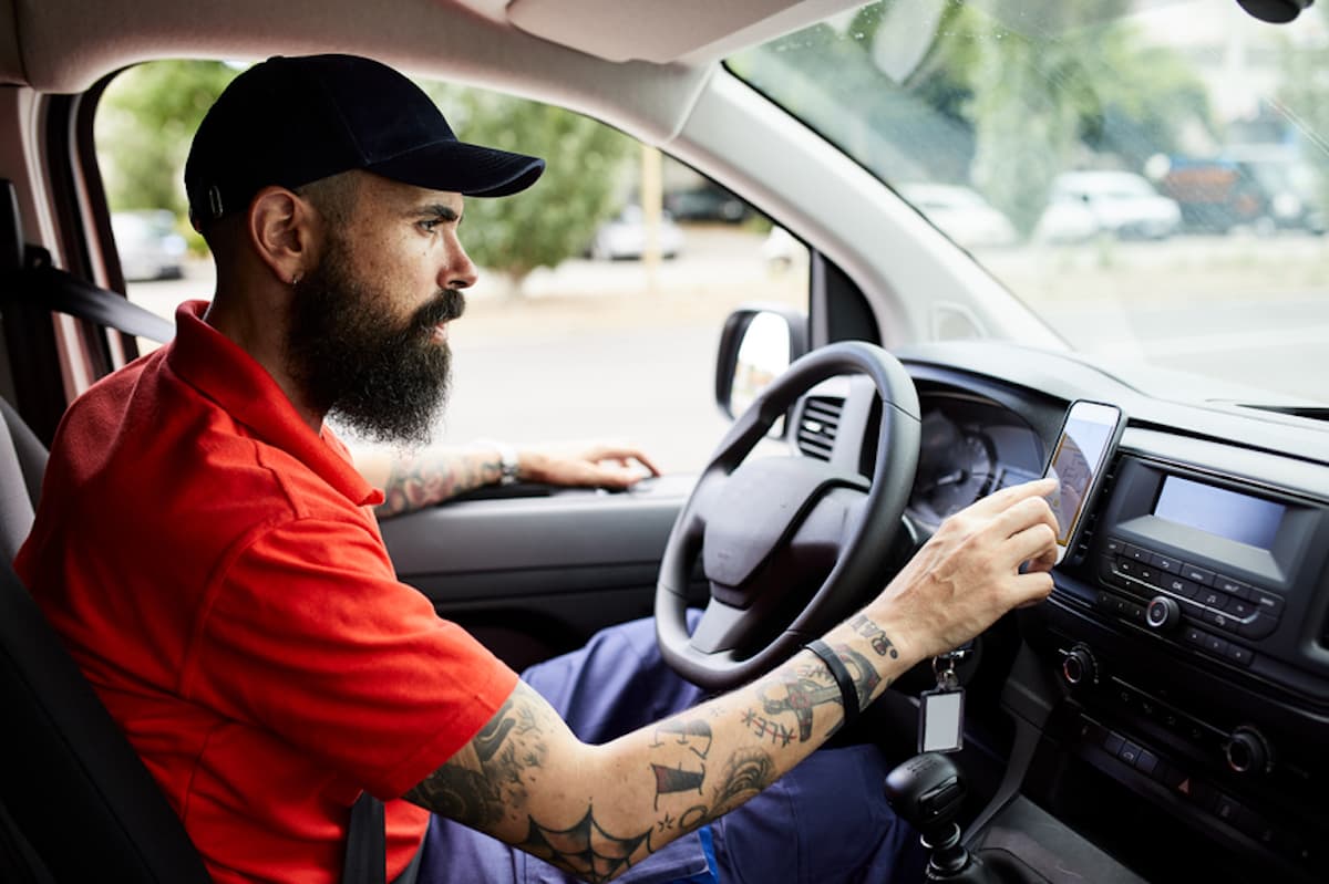 A rideshare driver taps his phone to operate the GPS.