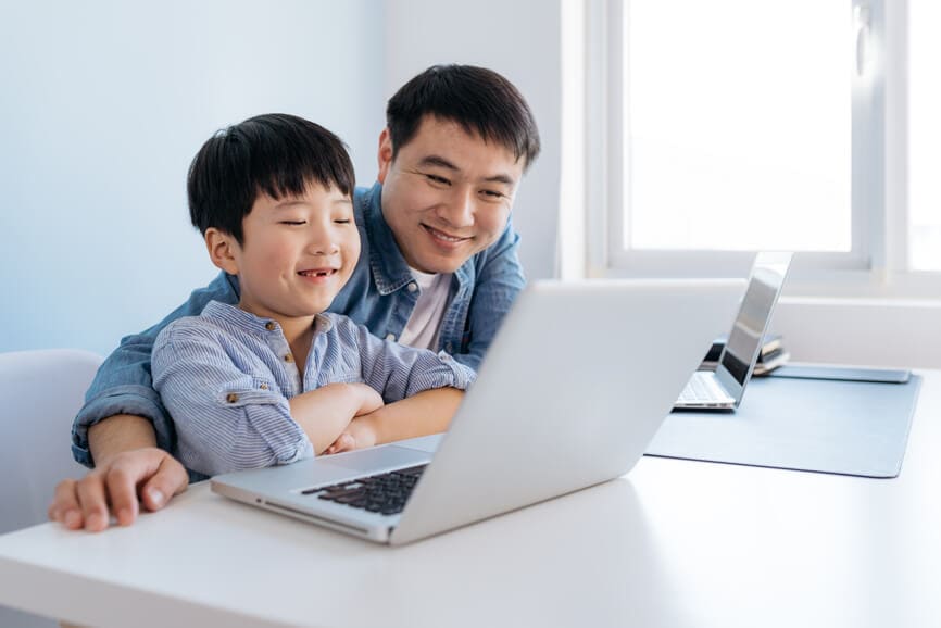 Father at home helping son with online school work.