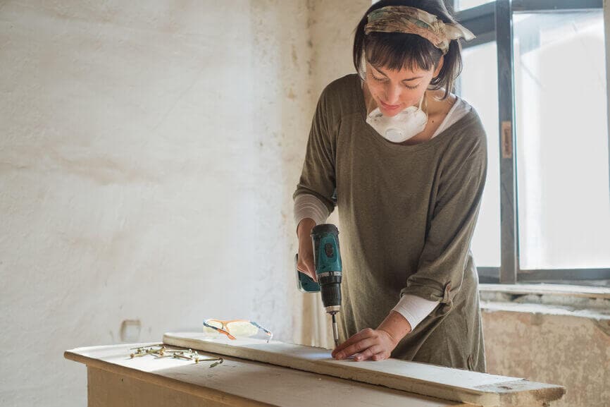 woman using a drill on wood planks renovating her home