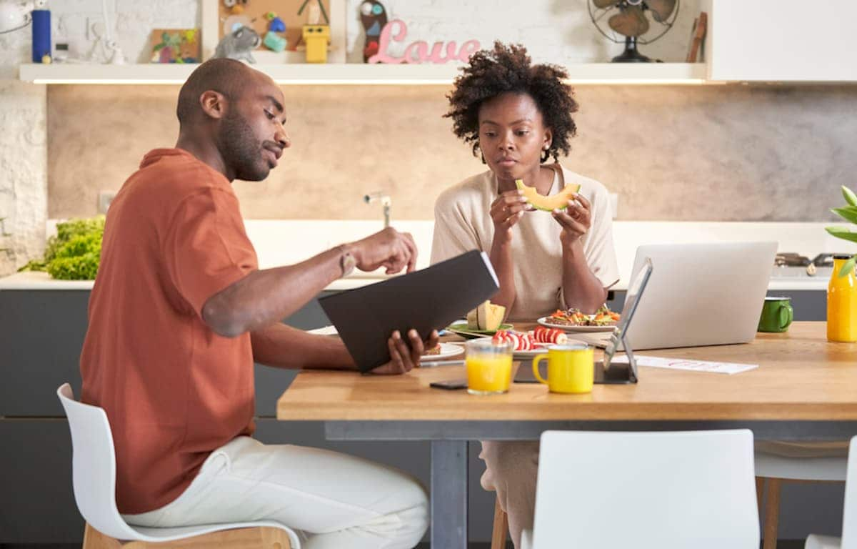 A pair of Black freelancers collaborates at a table over lunch.