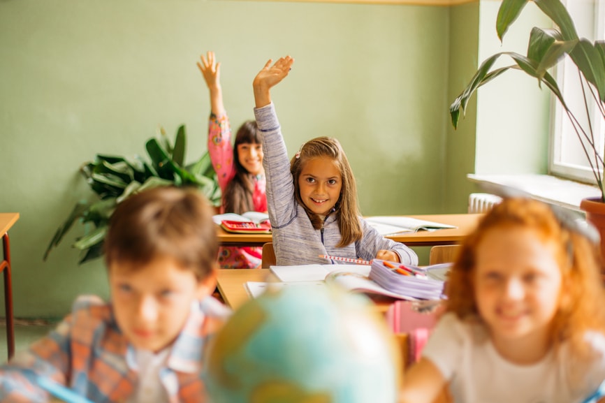 Little girl raising her hand in class