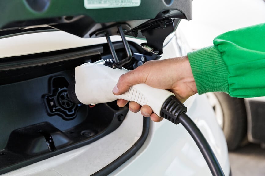 A person plugging in an electric car at a charging station.