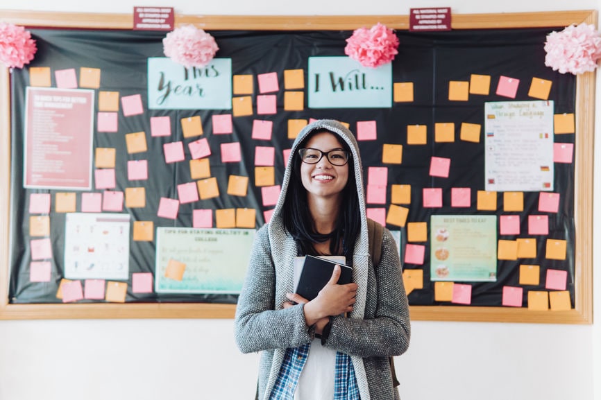 Happy female student holding books at a college campus