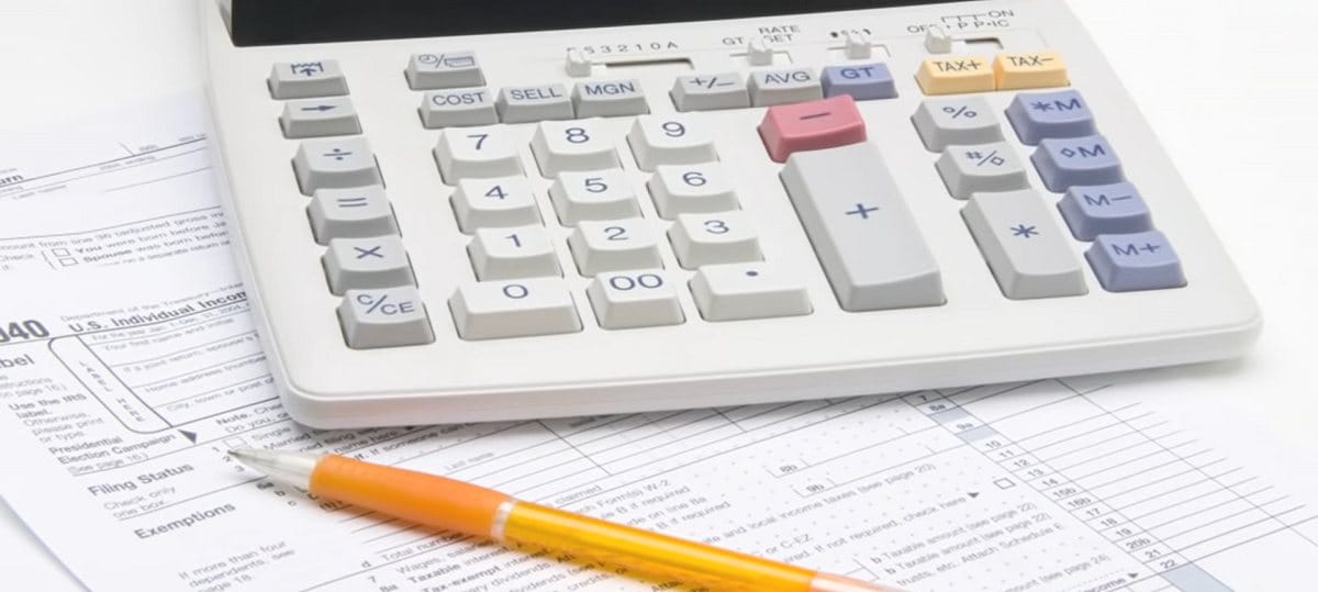 calculator and mechanical pencil lying on top of tax forms