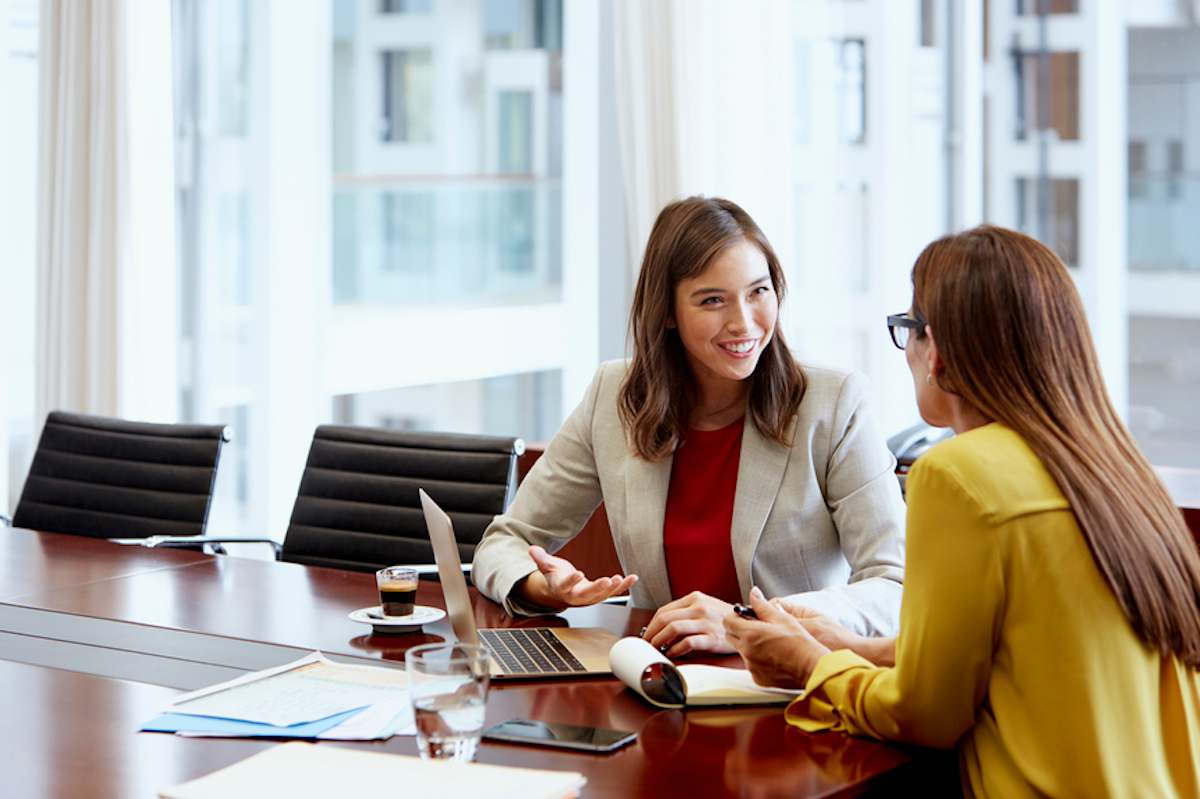 Smiling businesswoman meets with female colleague at table in office