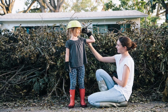 Mother and daughter work to clear debris near their home after a hurricane.