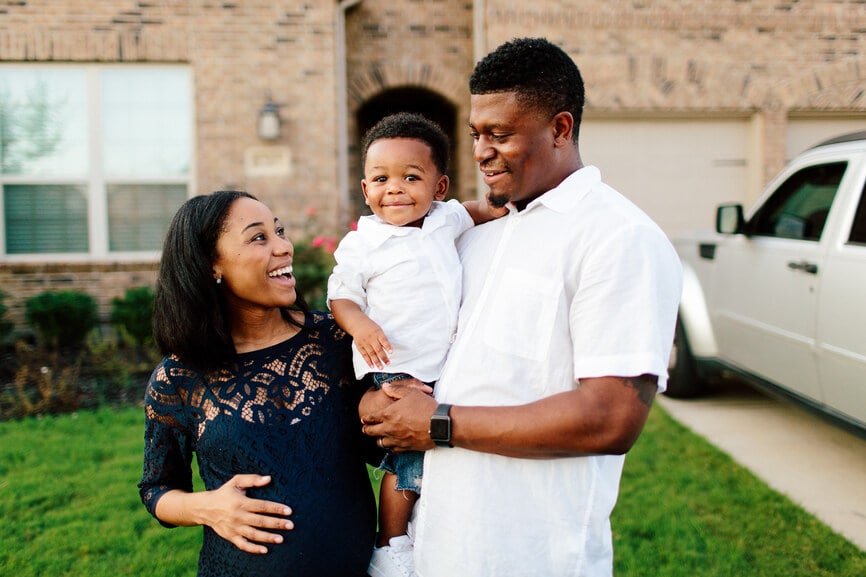 Happy family of three in front of their home.