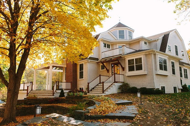 A 2-story home and tree at sunset.