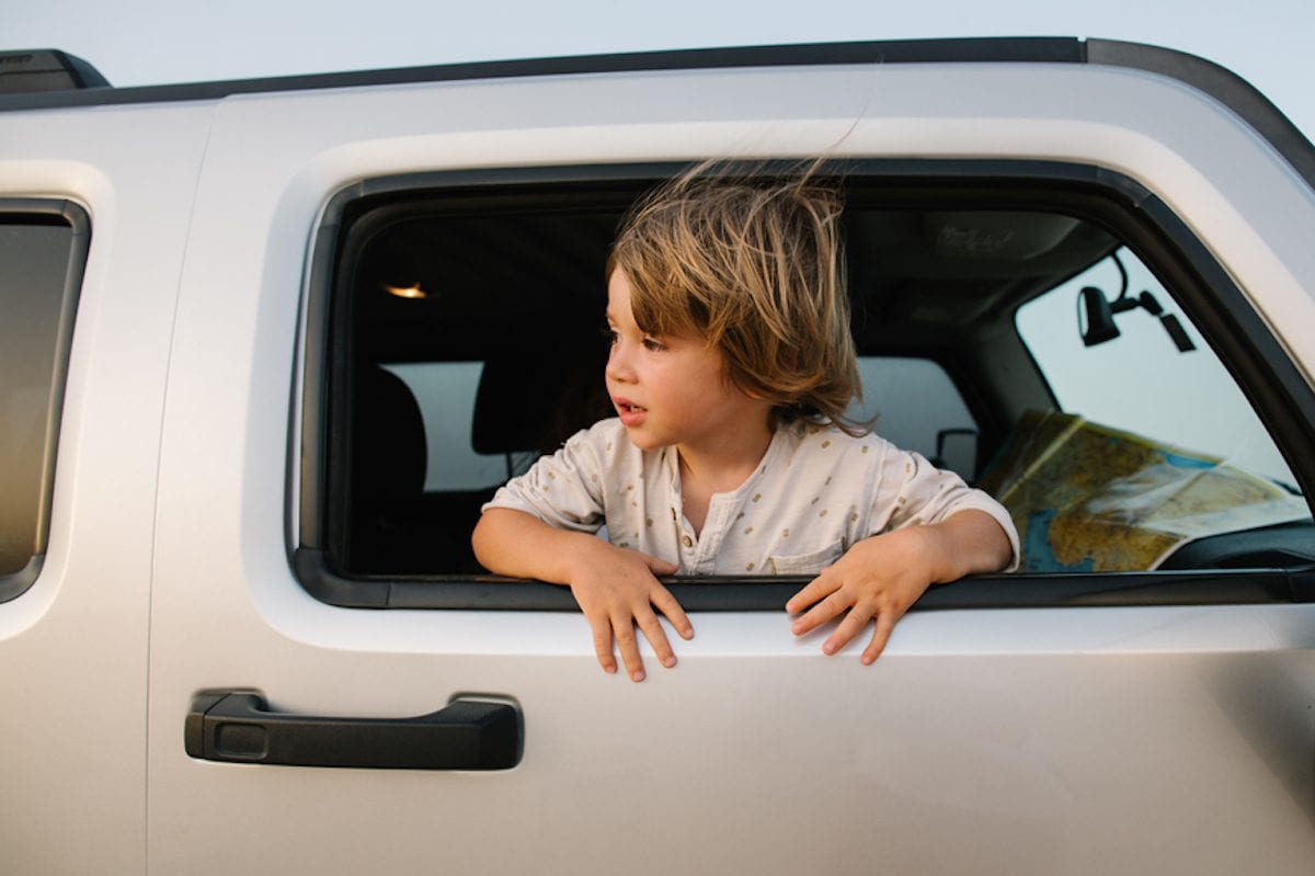 child standing in open window of car