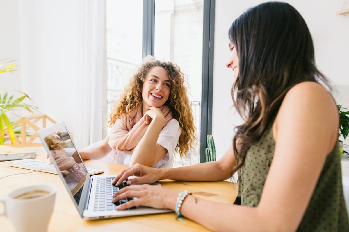 Two people sitting at a table with a laptop.