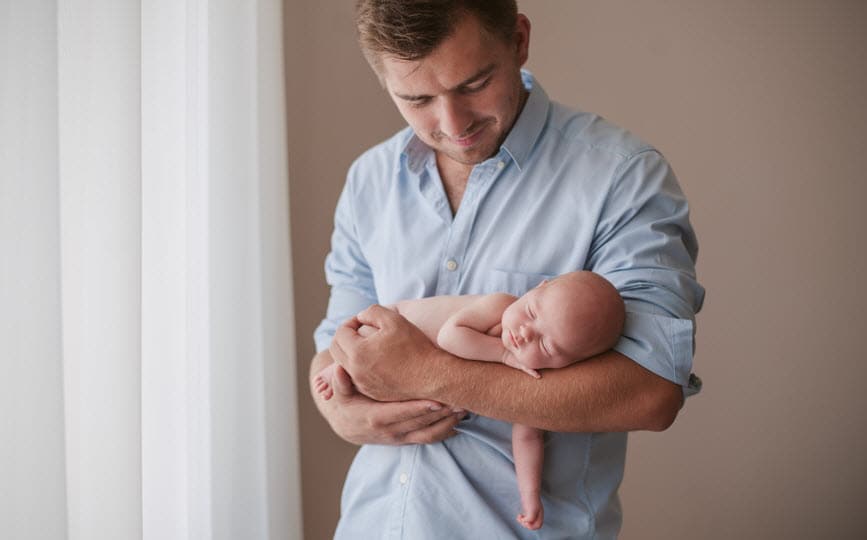 Proud father holding a sleeping newborn baby