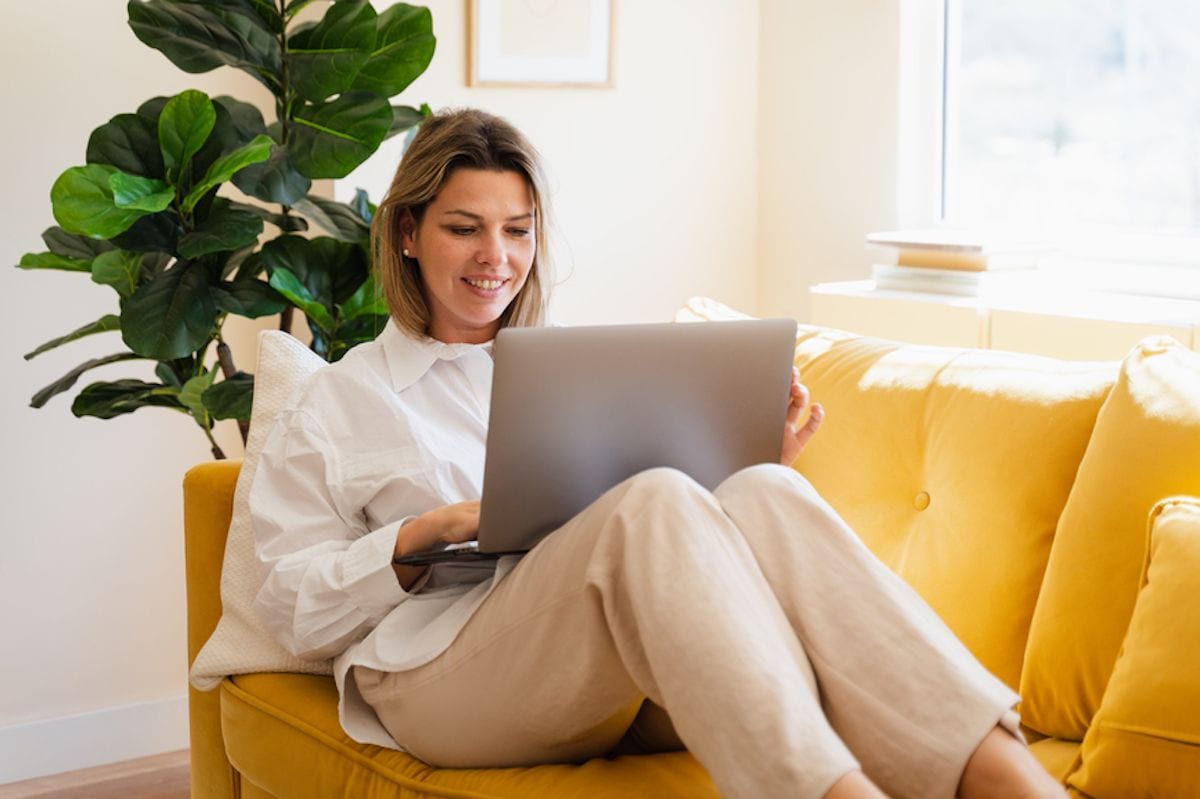 A person sitting on a couch with a laptop.